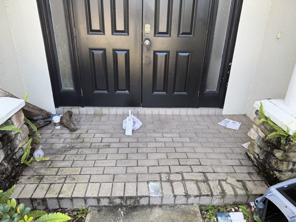 A delivery bag and coffee cup left directly on a brick porch floor by the front door