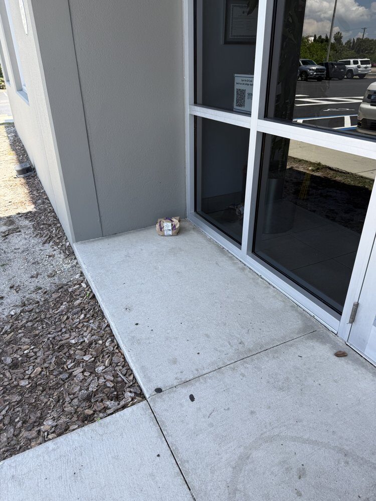 A small package left in a dirty concrete corner at a business entrance