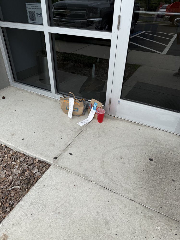 A takeout bag and drink leaning against a glass office storefront door